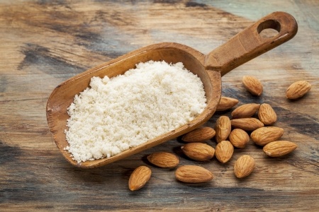 Photo of almond flour and whole, raw almonds. Almonds are a gluten-free food often used as a healthy snack and in baking.